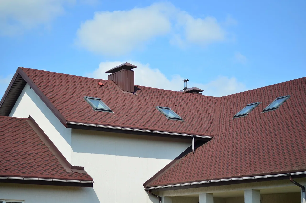 Maison couverte de tuiles sombres, plusieurs fenêtres de toit réparties sur le versant