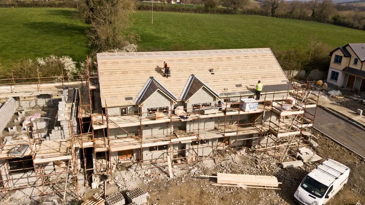 Maison en cours de rénovation vue d'en haut : couverture neuve posée, échafaudage en place et matériaux au sol