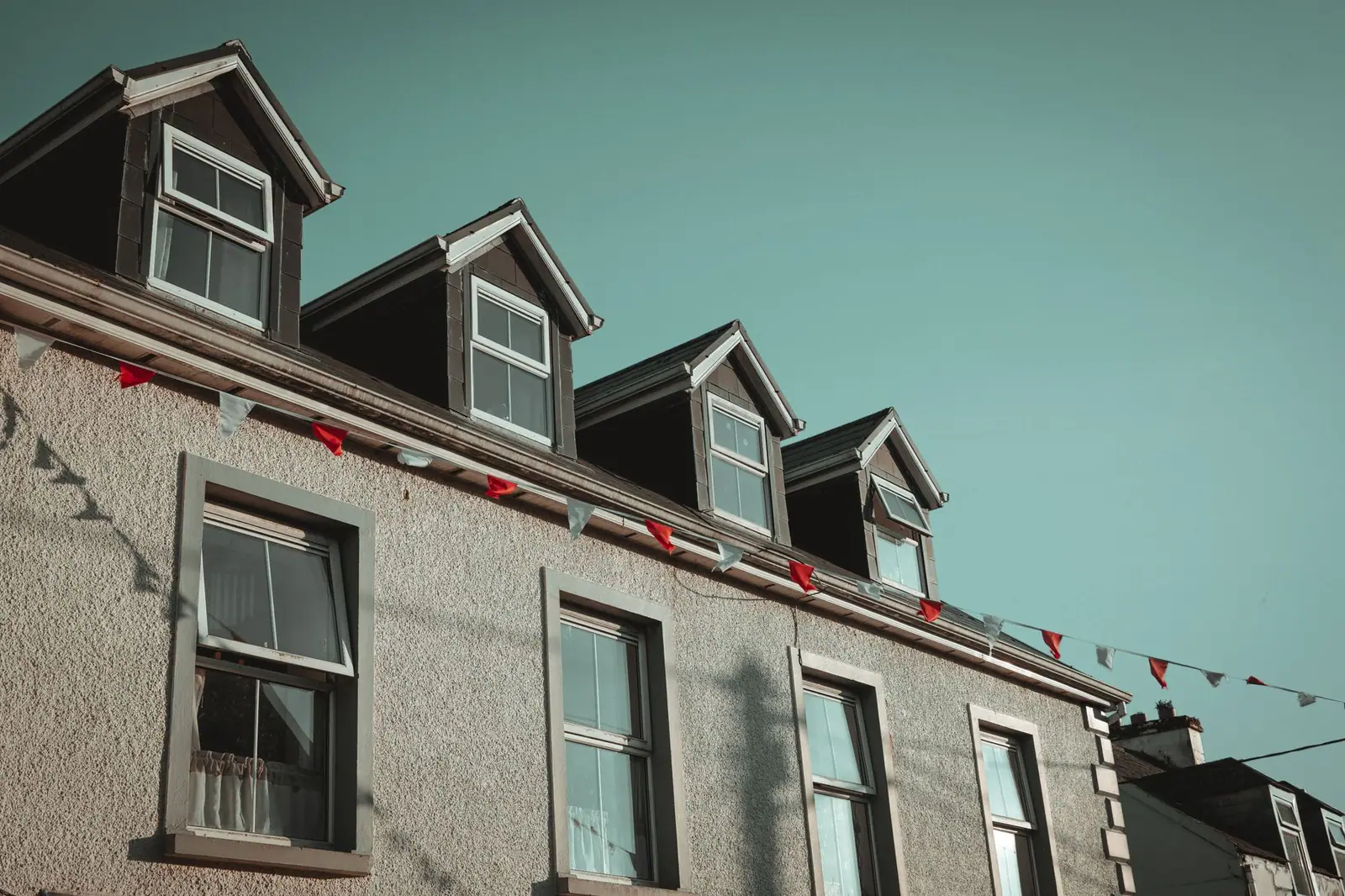 Alignement de lucarnes à deux pans sur la façade d'un bâtiment, chacune coiffée d'un petit toit en pointe