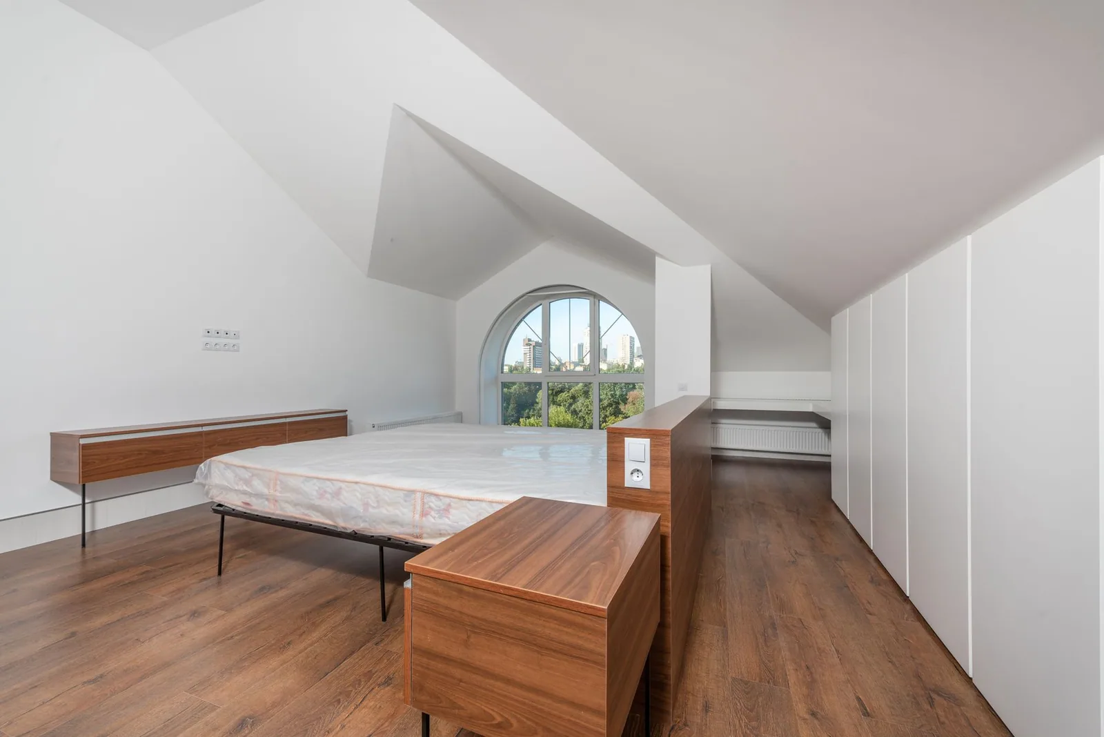 Chambre aménagée sous les combles, plafond suivant la pente du toit et lit placé sous le rampant