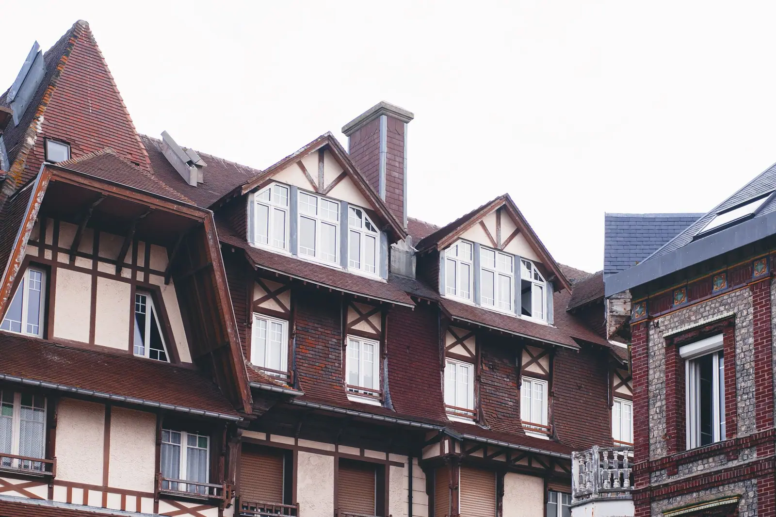Immeuble ancien à colombages avec sa toiture en tuiles et ses lucarnes alignées, vu depuis la rue