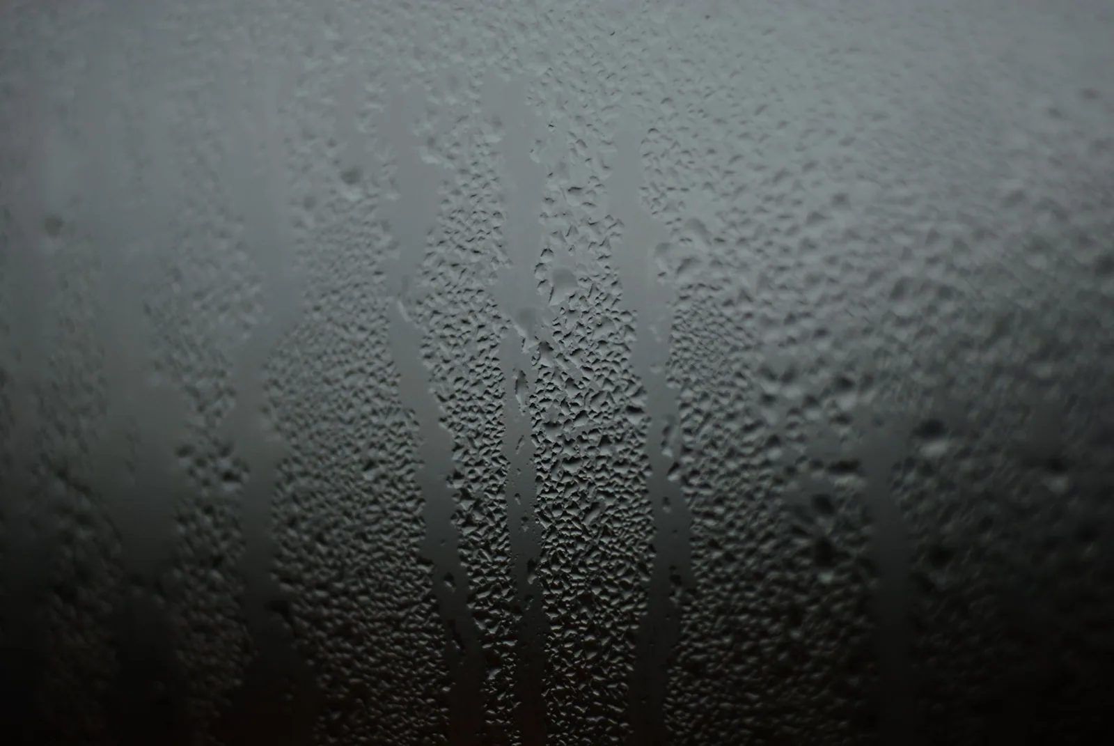 Fines gouttes d'eau déposées sur une surface froide et sombre