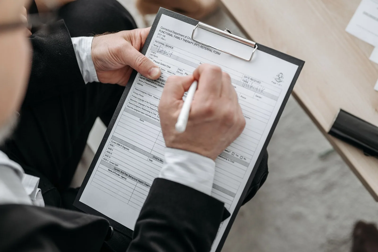 Mains signant un formulaire posé sur une planchette à pince