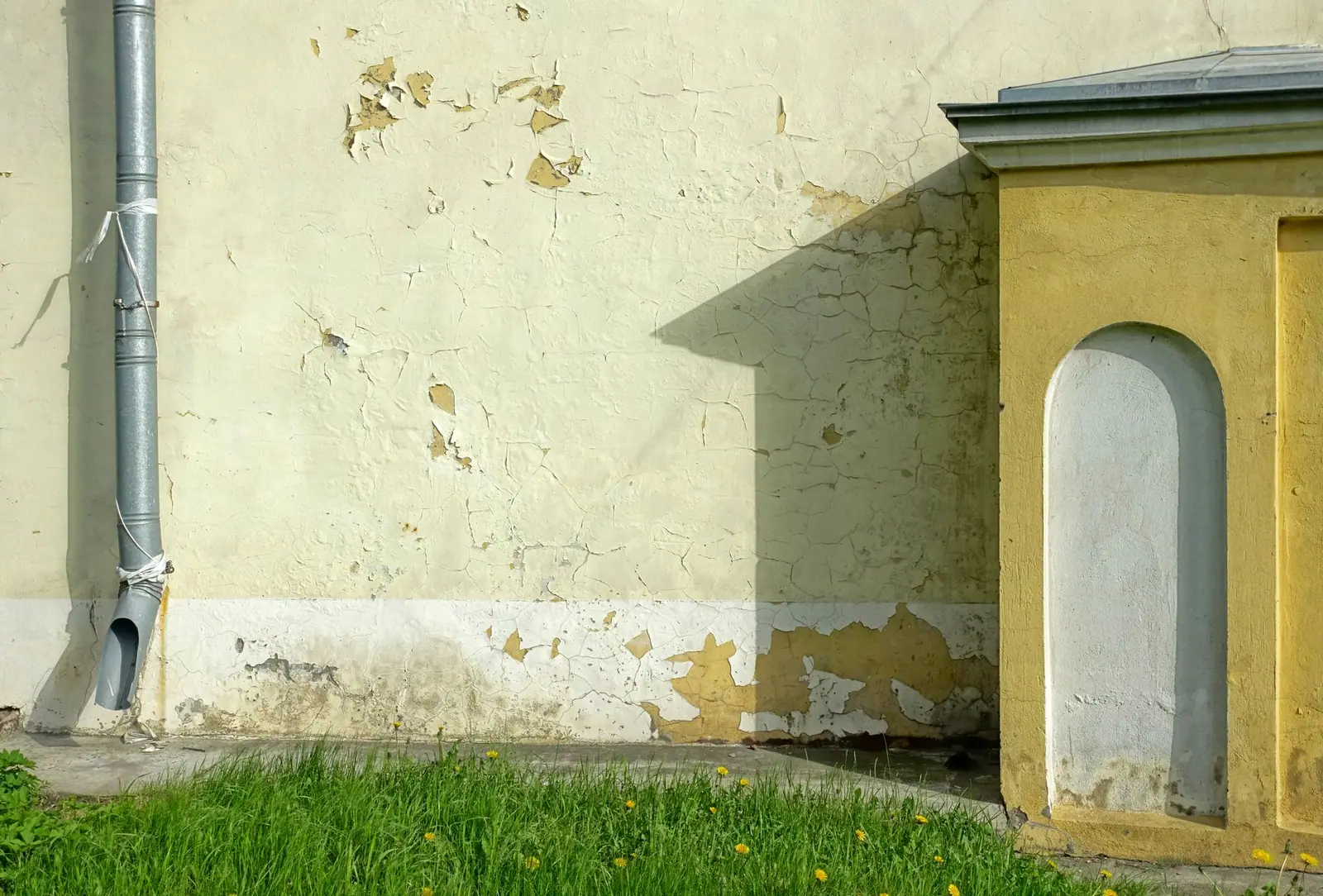 Descente d'eau métallique fixée sur la façade enduite d'une maison ancienne