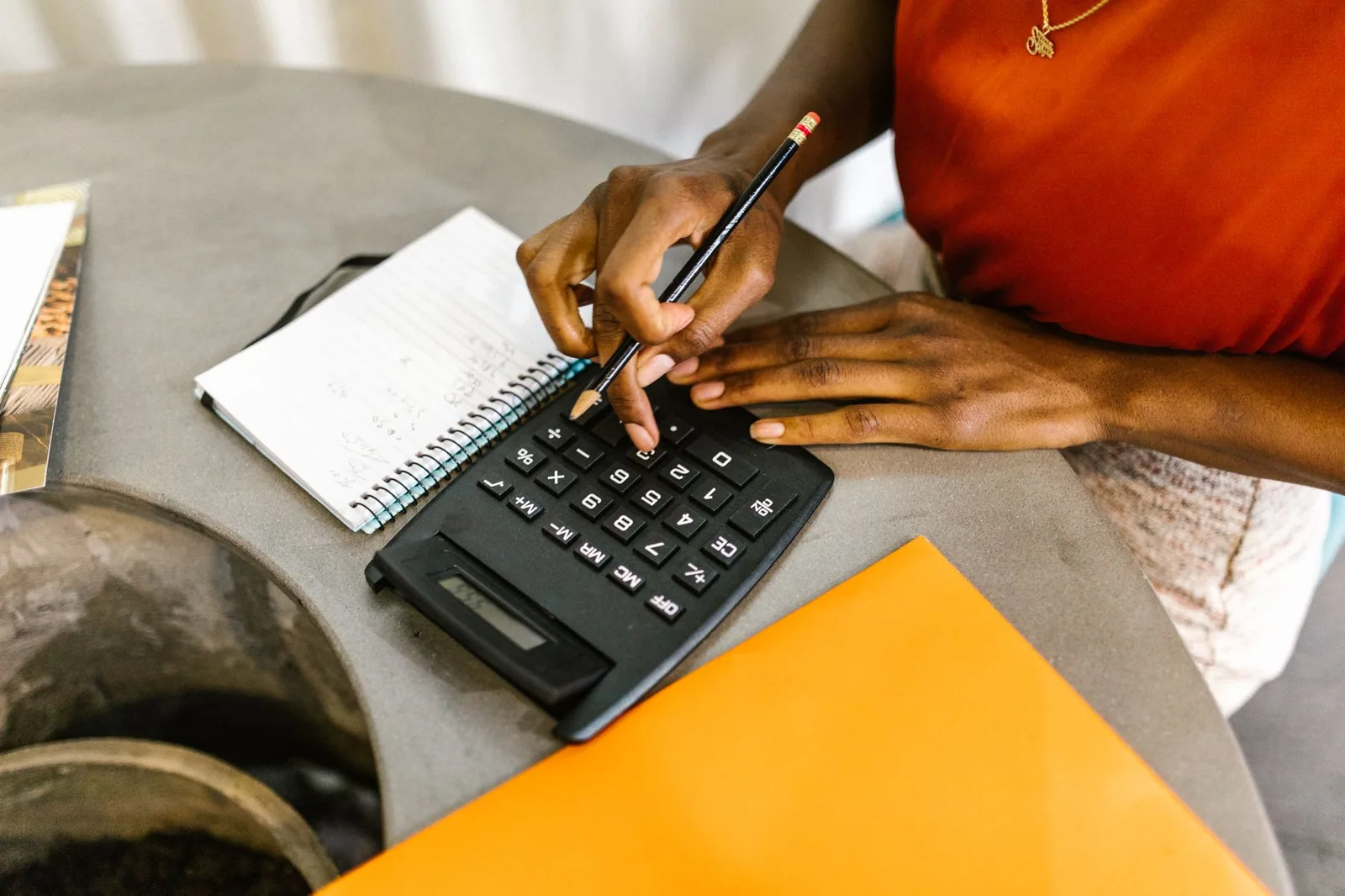 Bureau avec calculatrice, carnet, stylo et casque de chantier posé à côté