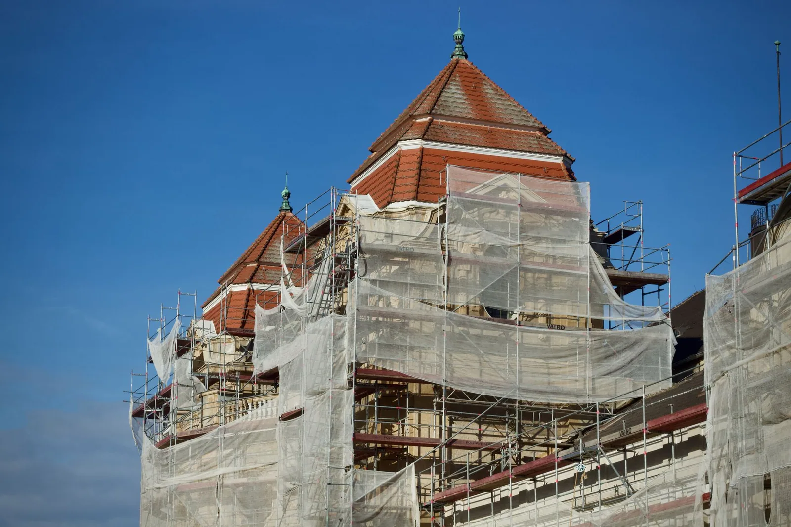 Bâtiment sous échafaudage, toiture en cours de reprise visible au-dessus