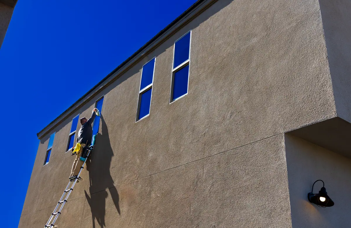 Échelle dressée contre la façade d'un bâtiment, jusqu'au niveau du débord de toit