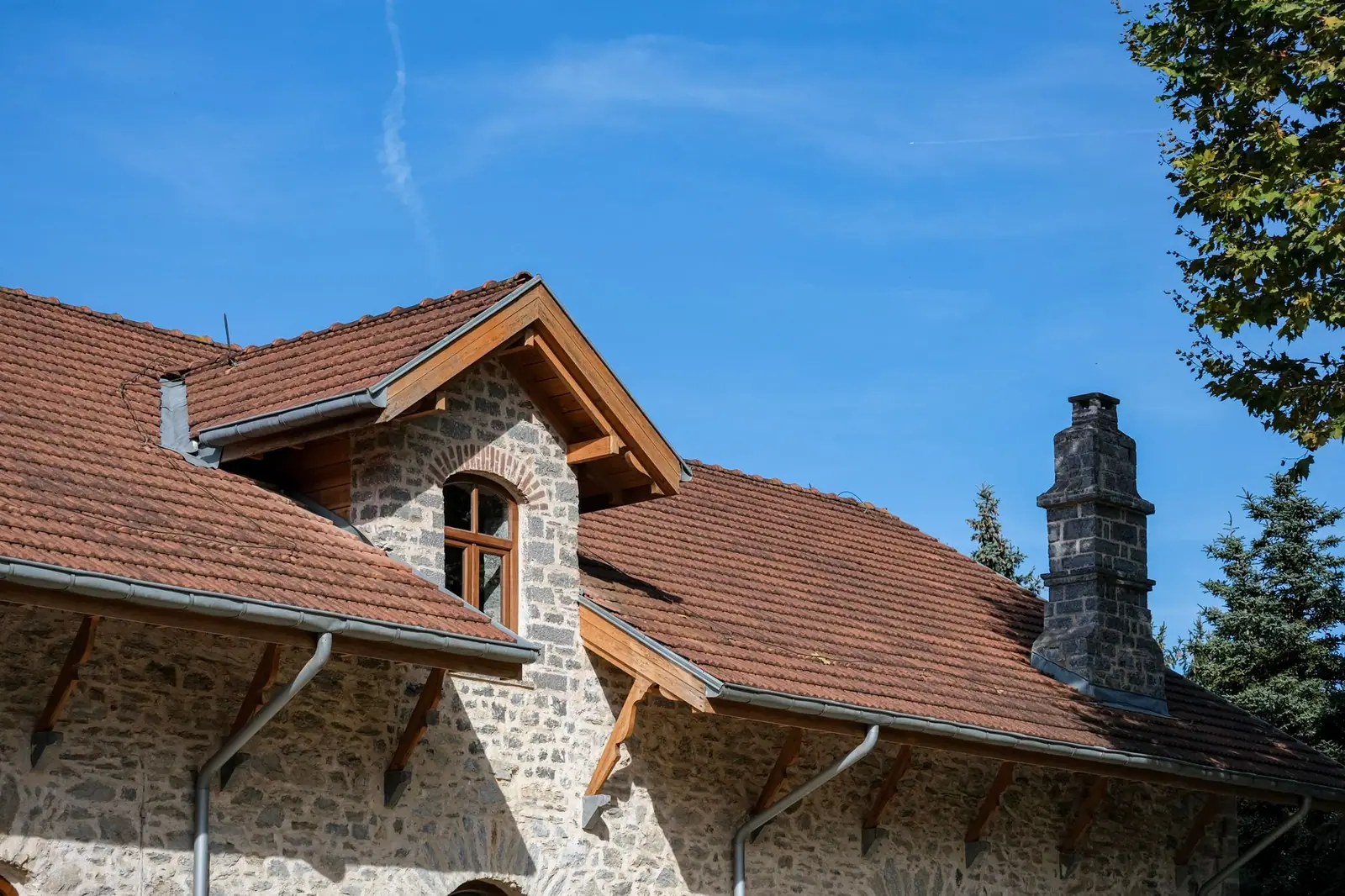 Maison en pierre avec couverture en tuiles, lucarne et souche de cheminée