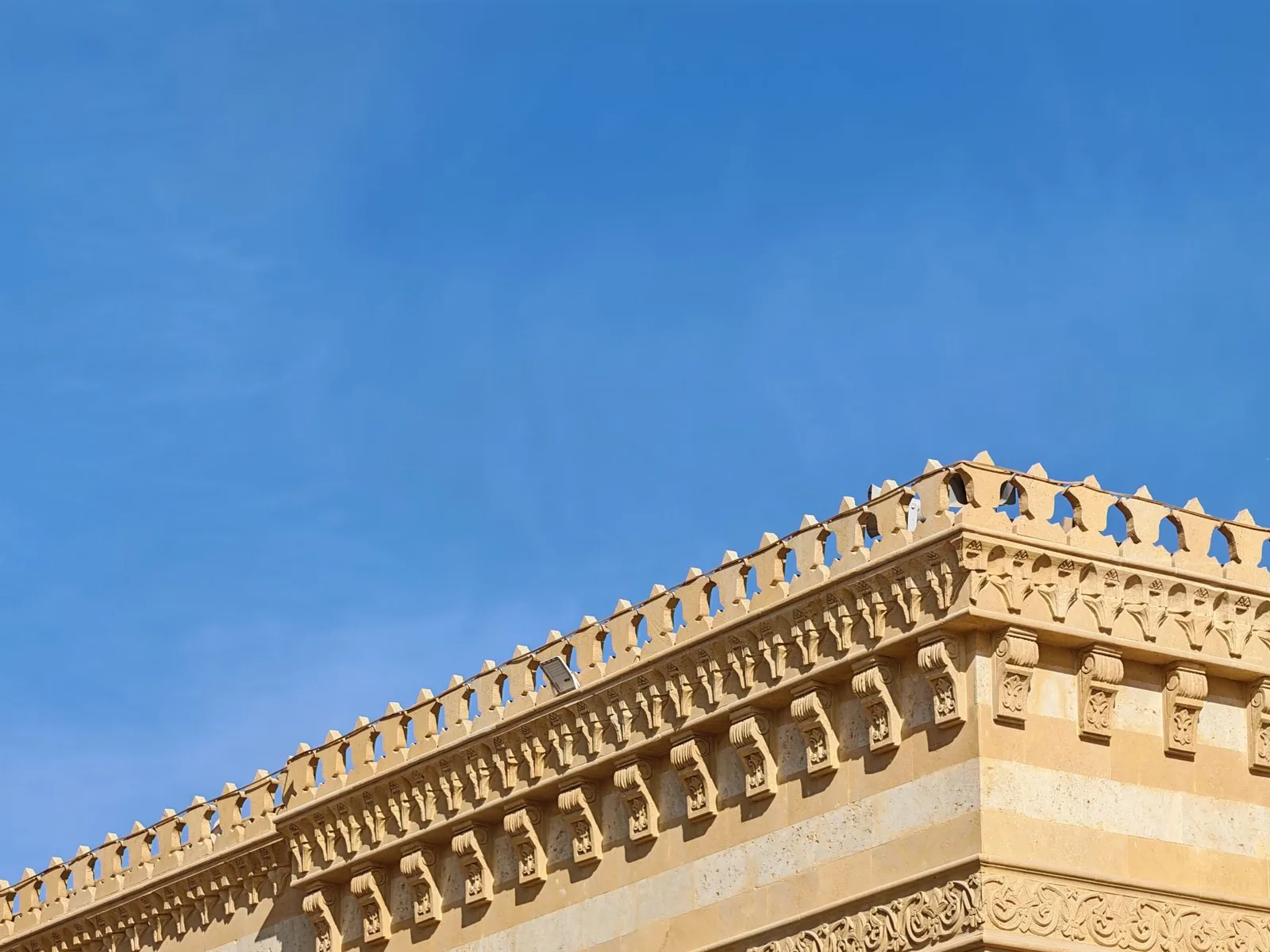 Corniche de pierre couronnant la façade d'un immeuble ancien, sans gouttière apparente
