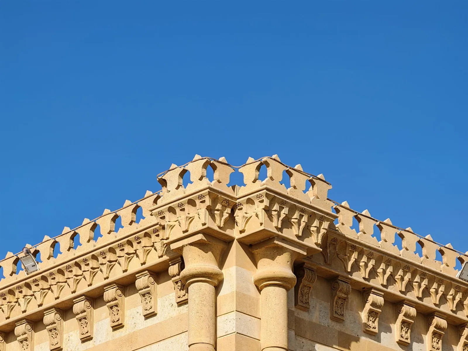 Angle d'un immeuble en pierre de taille, balustrade et corniche moulurée sur toute la longueur