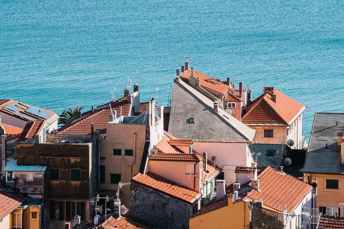 Maisons aux toitures de tuiles rondes descendant jusqu'au bord d'une eau turquoise