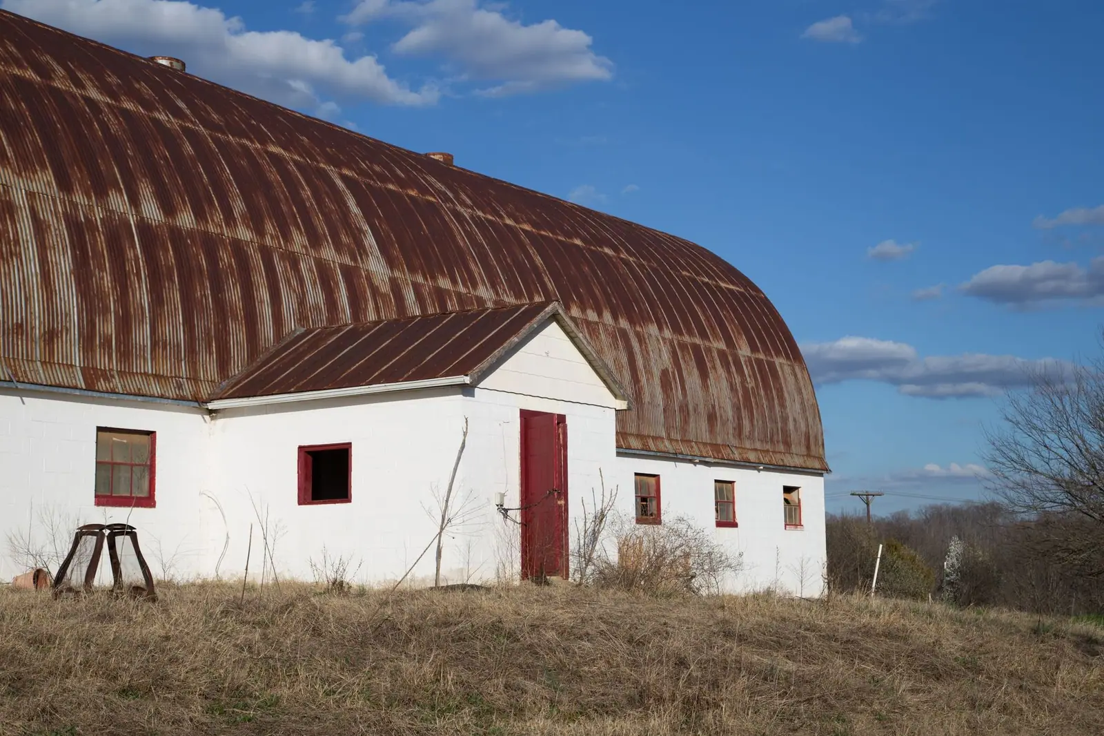 Bâtiment agricole coiffé d'une toiture ondulée rouillée, isolé dans un champ