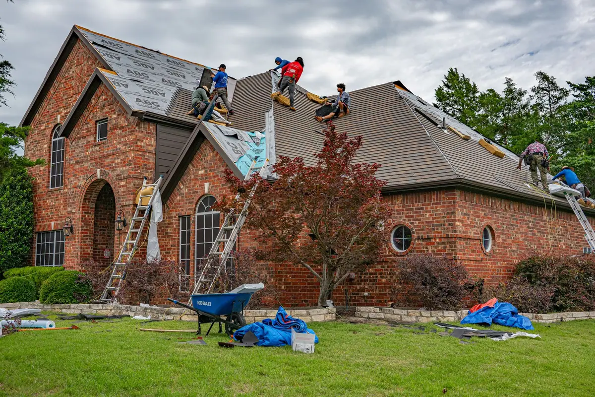 Maison en cours de réfection de toiture, échelles appuyées et bâches au sol