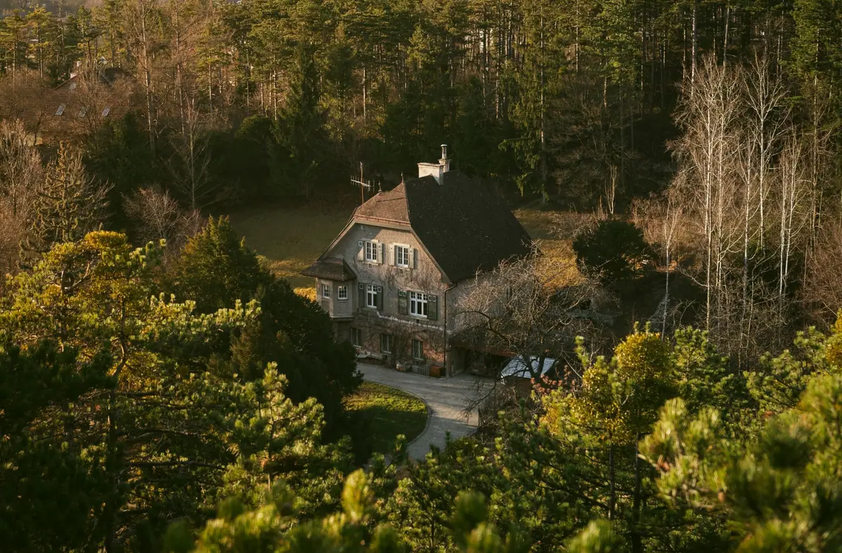 Maison isolée au milieu des arbres, vue depuis le dessus, entourée de forêt de tous côtés