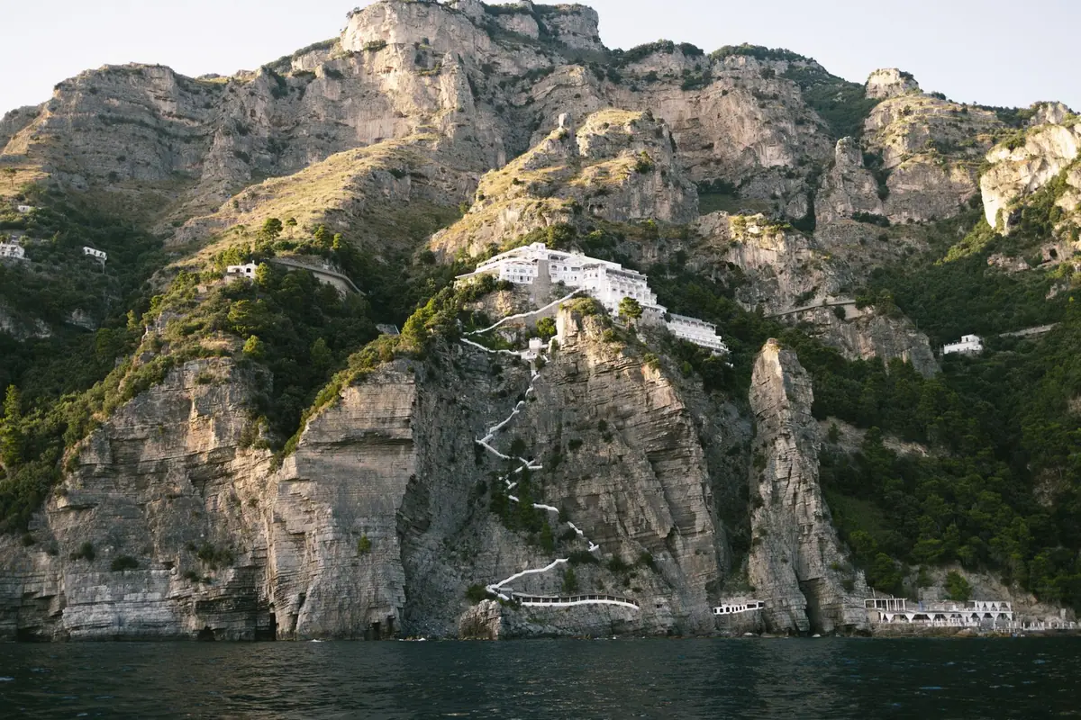 Maisons accrochées à une falaise rocheuse dominant la mer, reliées par des escaliers