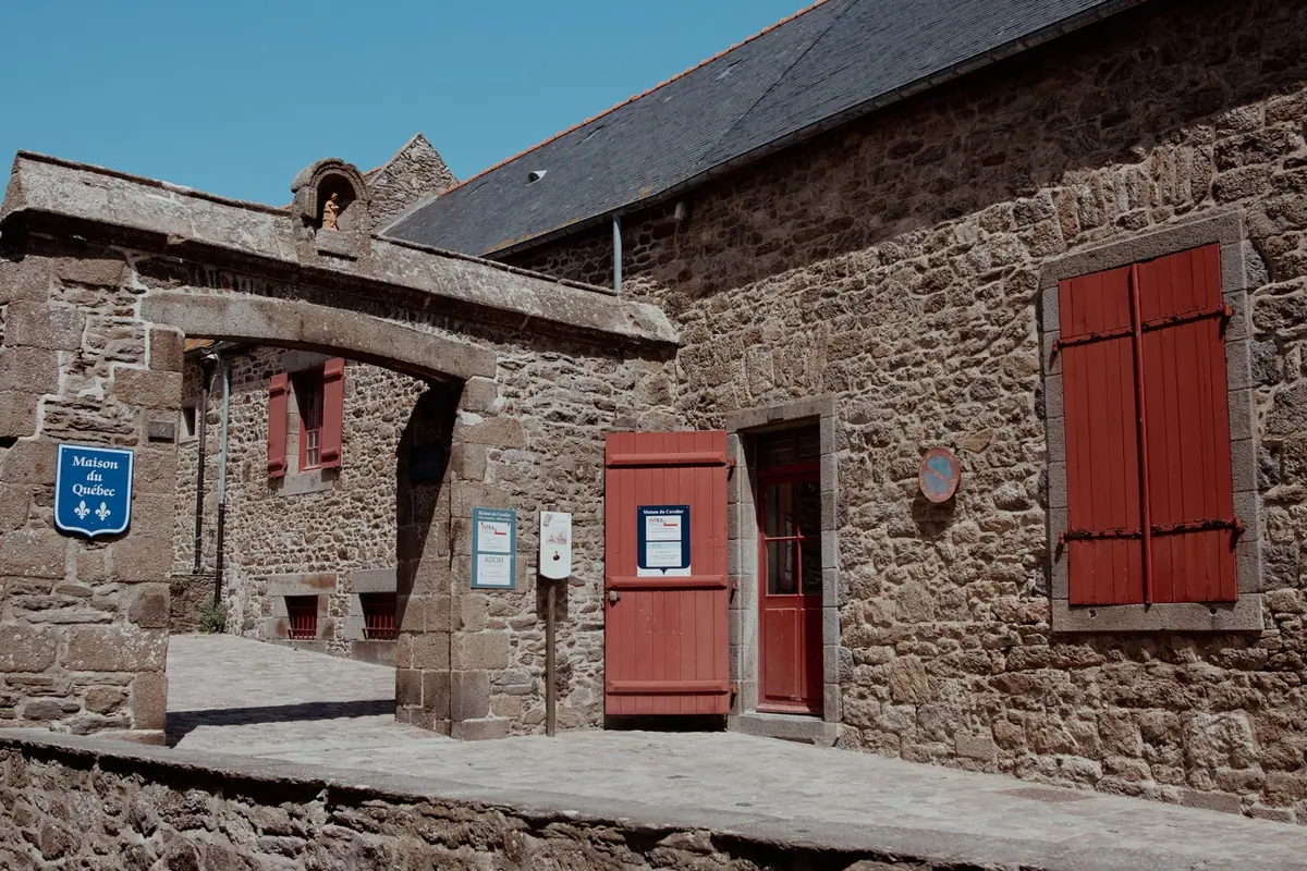 Bâtiment en pierre couvert d'ardoises, avec volets en bois peints