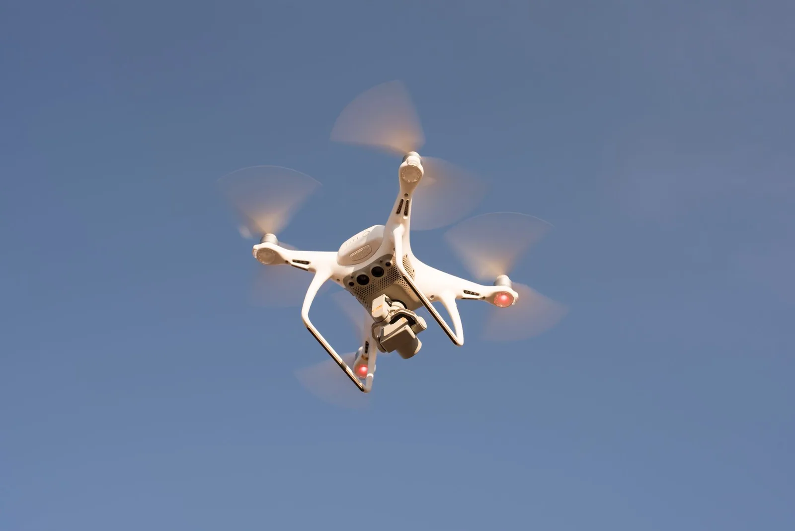 Drone en vol stationnaire, vu en contre-plongée contre le ciel