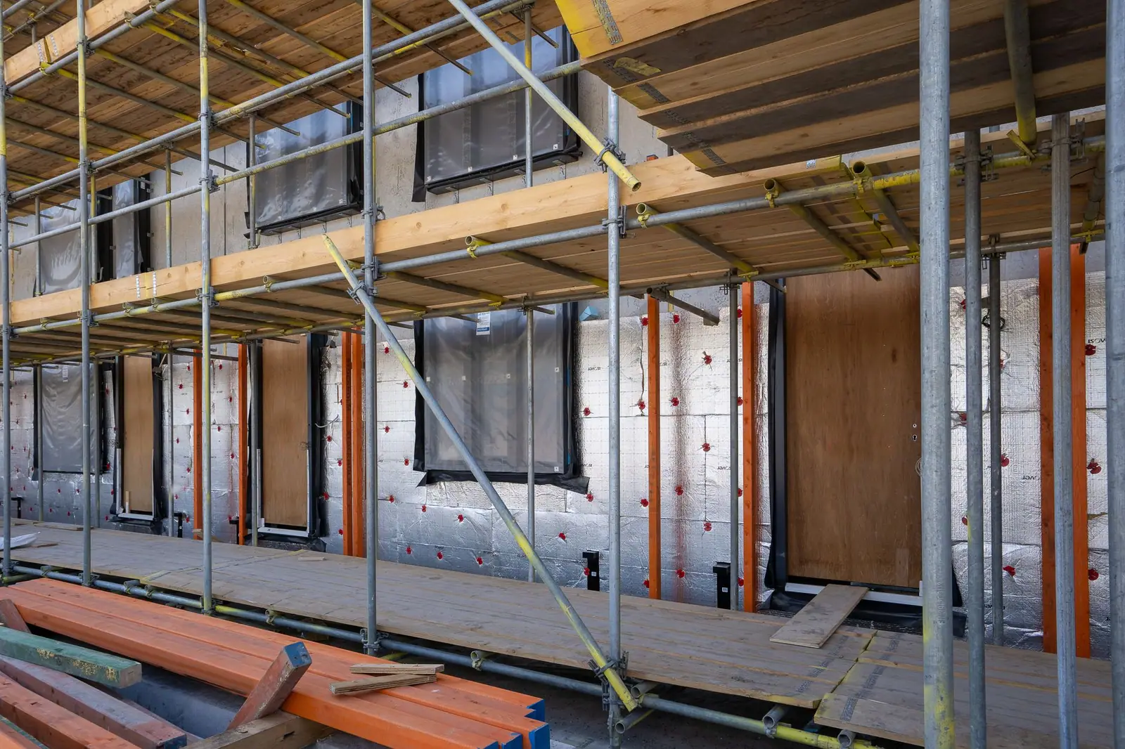 Panneaux en cours de pose sur une construction entourée d'un échafaudage