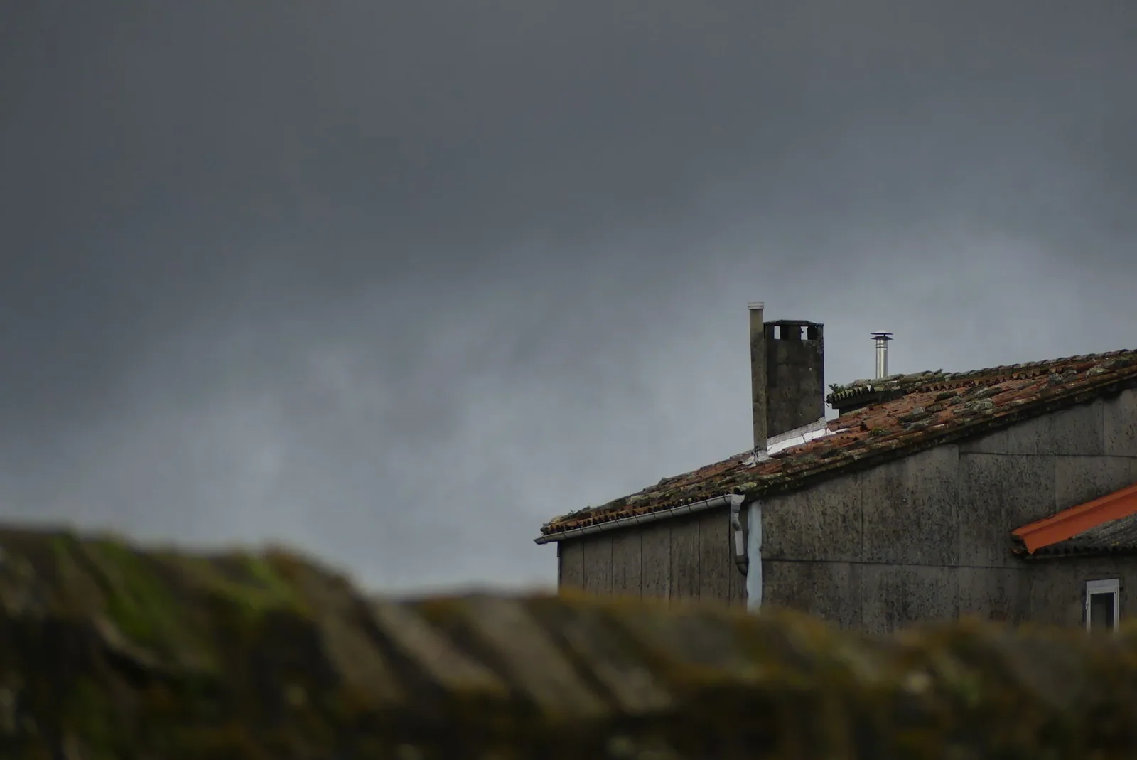 Ciel d'orage très sombre au-dessus d'une maison couverte de tuiles