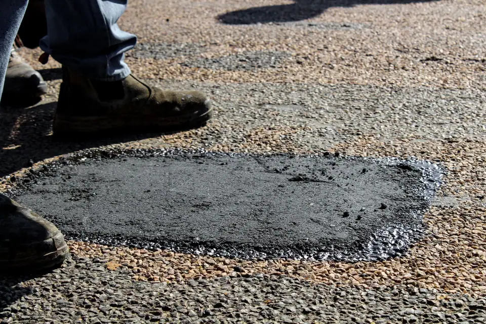 Pied posé au bord d'une réparation d'étanchéité fraîche sur un toit plat gravillonné