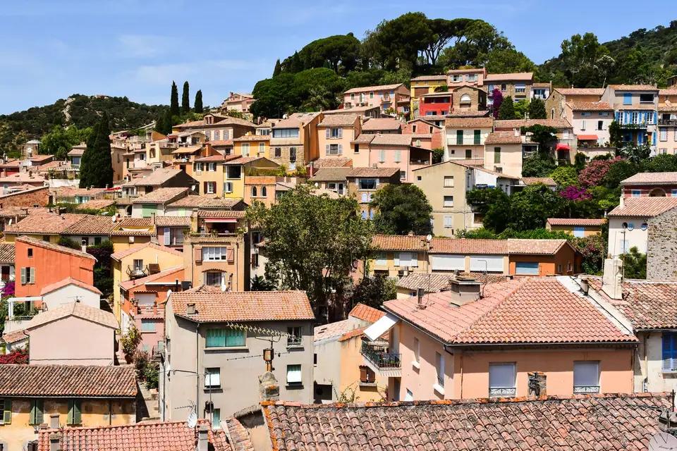 Village perché aux toits de tuiles terre cuite, étagé à flanc de colline parmi les cyprès