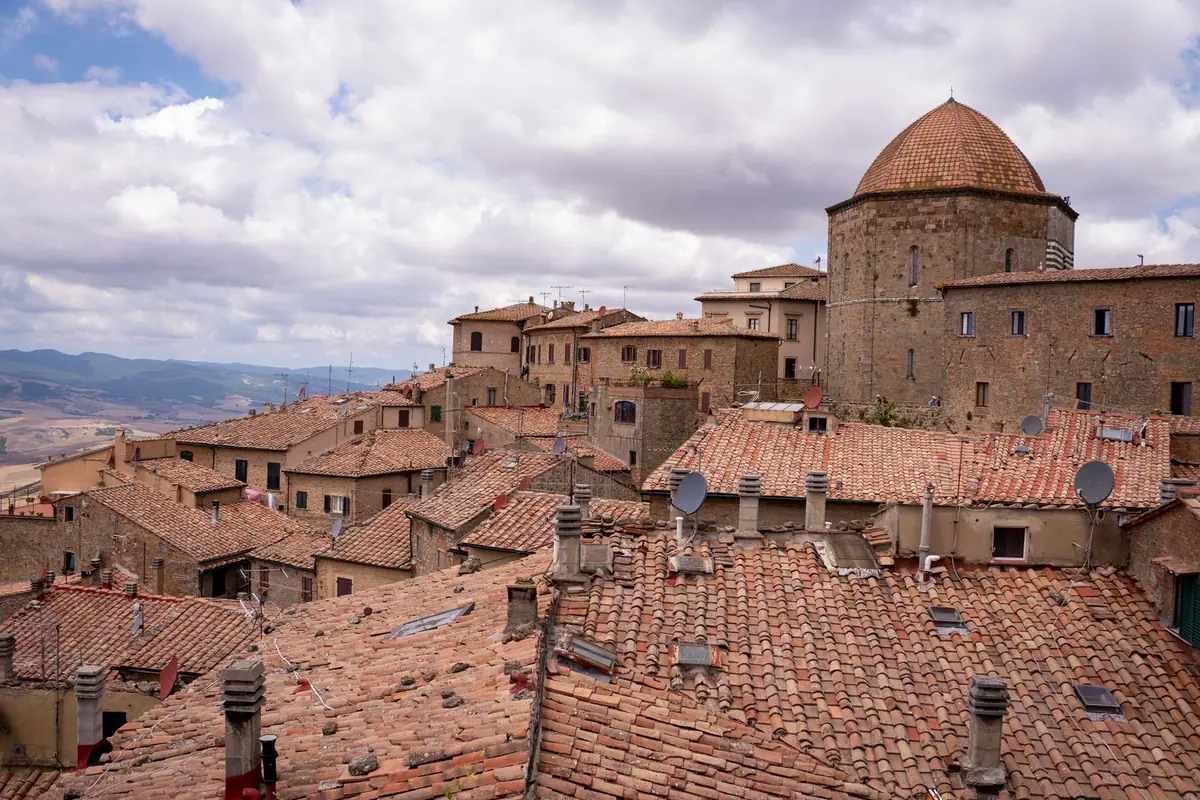 Toitures d'un village ancien vues depuis les hauteurs, tuiles rondes patinées et cheminées maçonnées