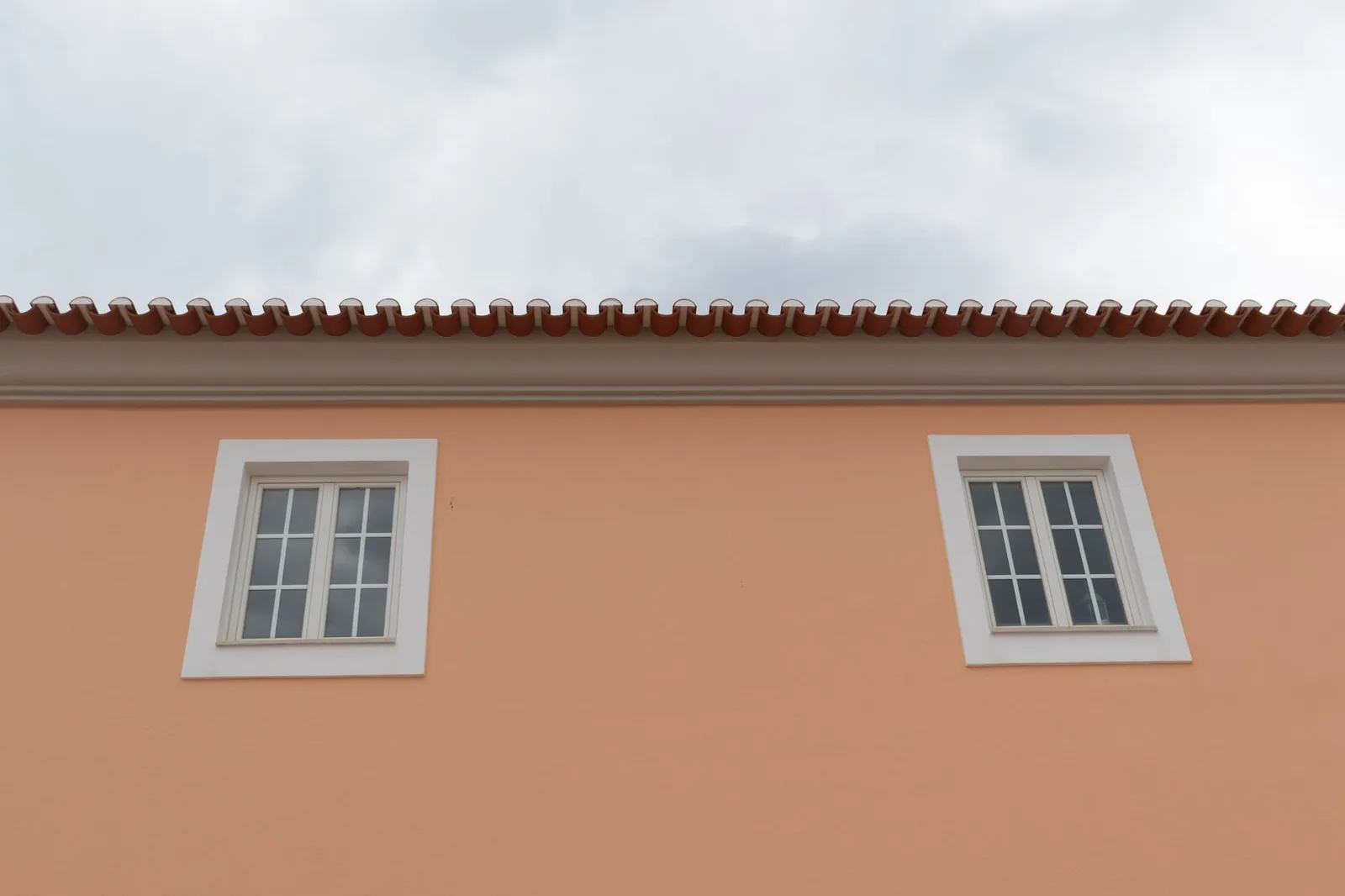 Façade d'une maison aux ouvertures alignées, couverture visible au-dessus