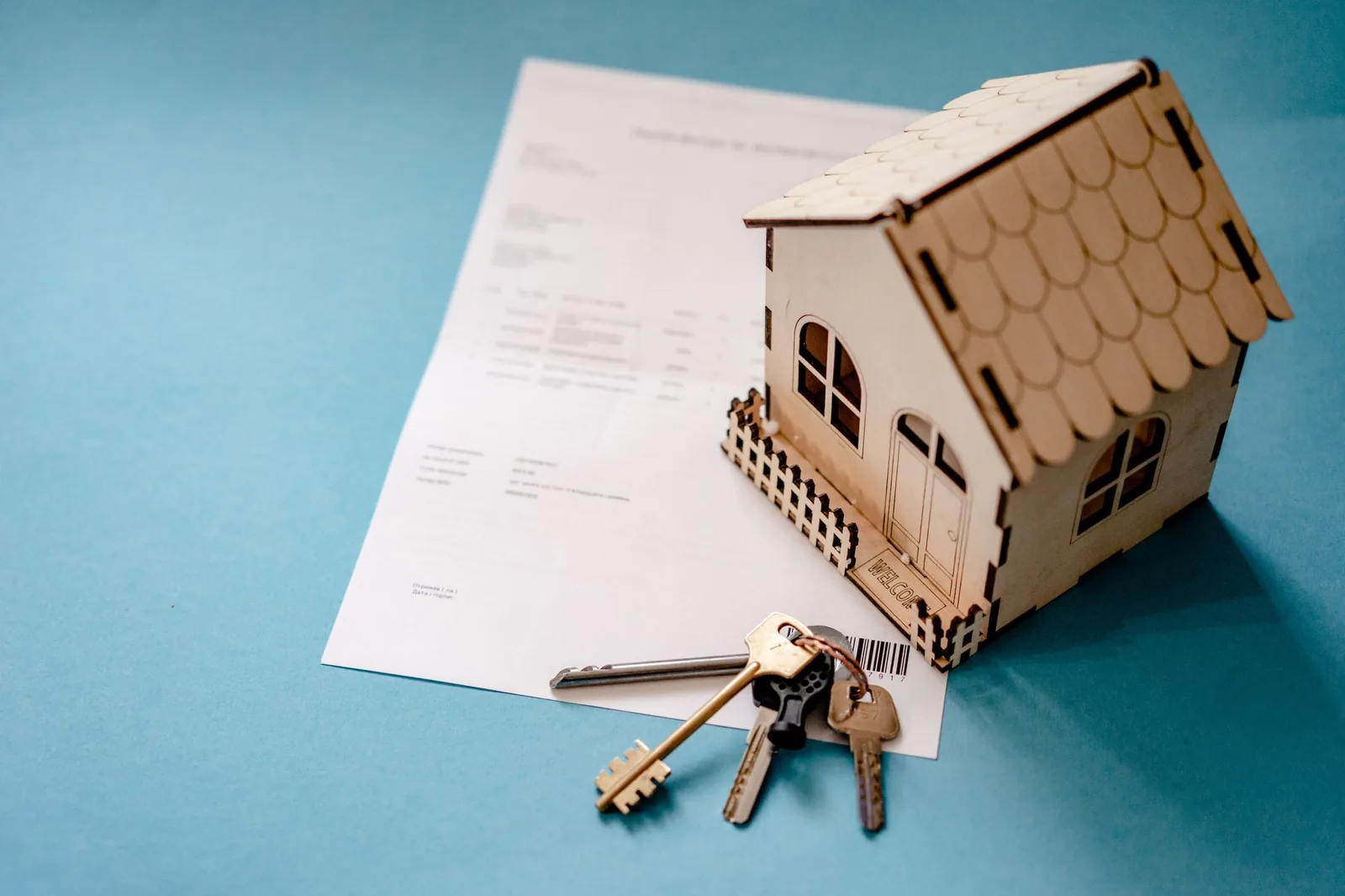 Maquette de maison en bois posée près d'un jeu de clés et d'un document