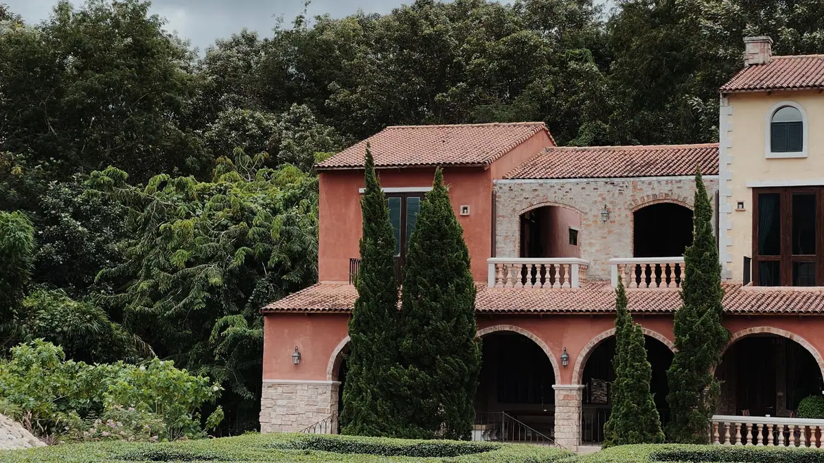 Villa méditerranéenne à toiture de tuiles rondes, entourée de cyprès et de végétation