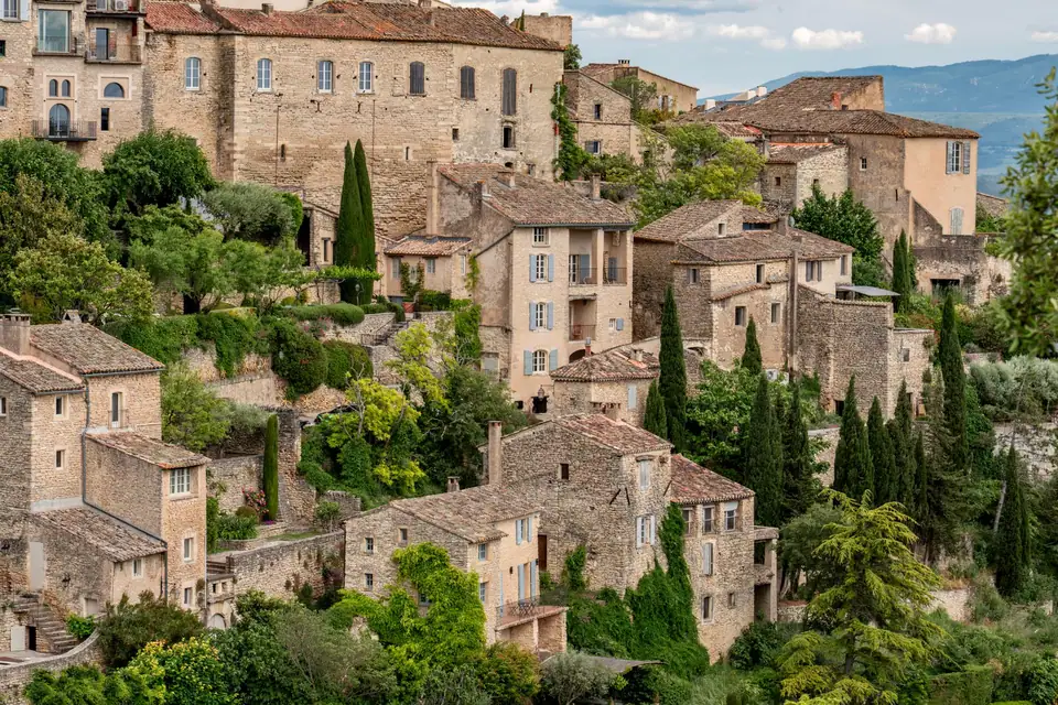 Village provençal perché à flanc de colline, maisons en pierre et toitures de tuiles canal étagées