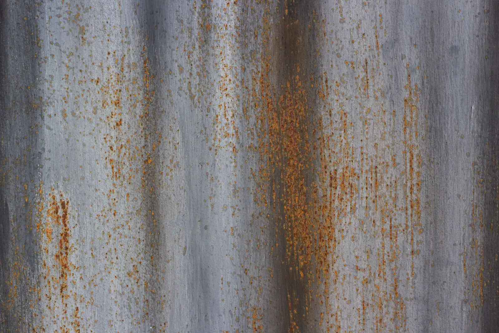 Surface métallique de couverture marquée par des coulures de rouille sur toute sa hauteur