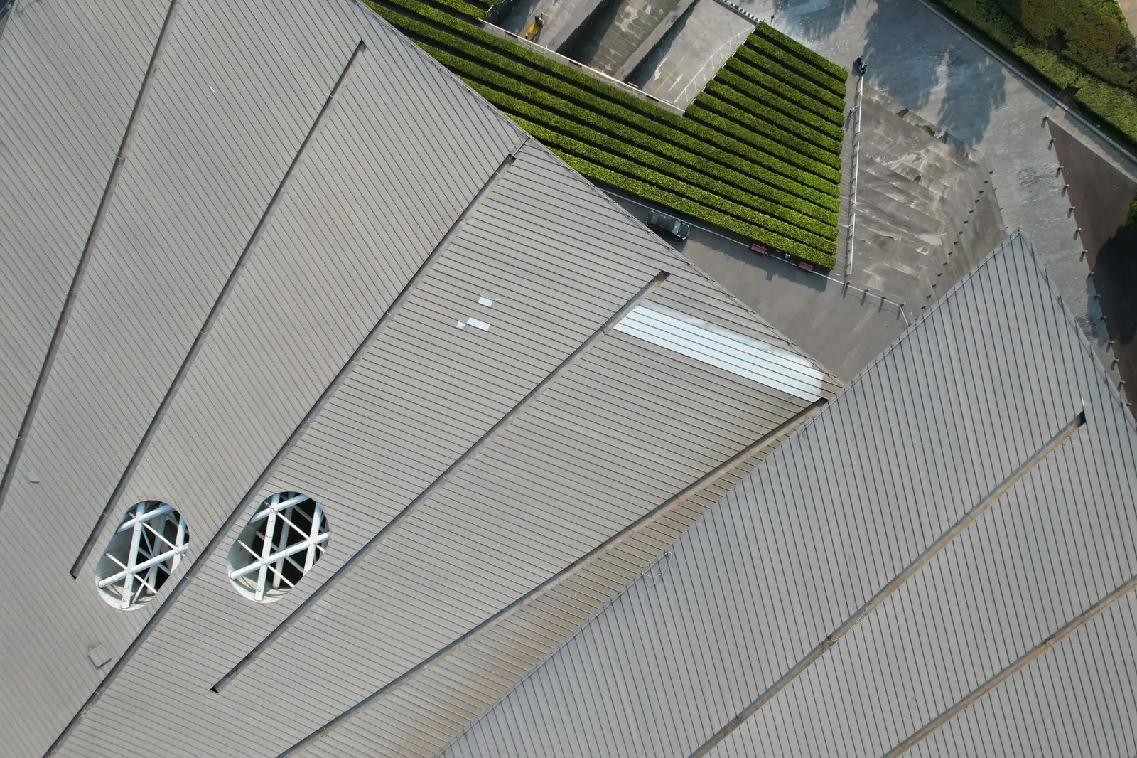 Toiture métallique claire vue du dessus, avec ses joints réguliers et ses sorties rondes